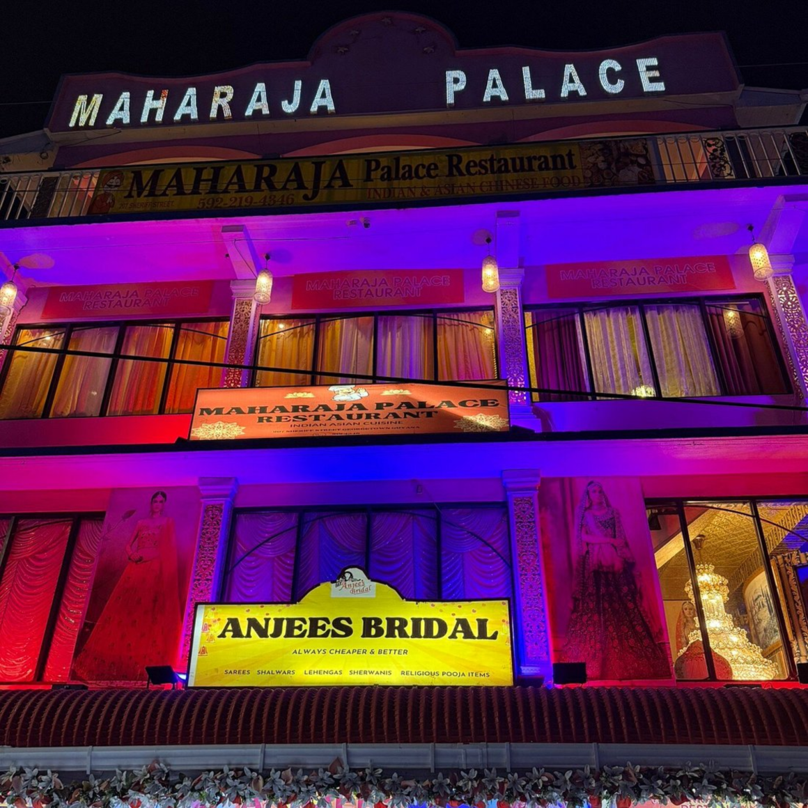Night view of brightly lit building with Maharaja Palace Indian Indo-Chinese restaurant and Anjees Bridal shop, featuring colorful lights, cultural décor, and signage for sarees, lehengas, sherwanis, and pooja items